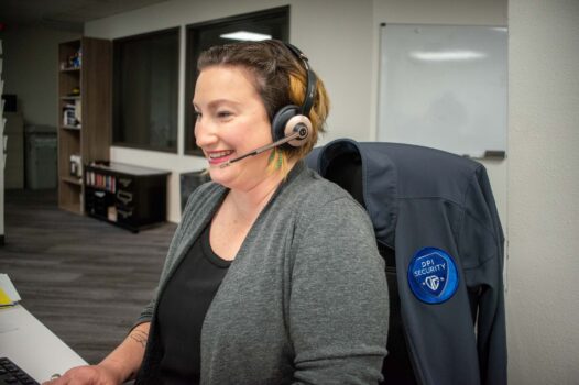 Smiling woman wearing headset sitting in chair with DPI Security jacket